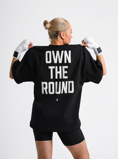 Female model showing OWN THE ROUND back print on black One Bout Oversized T-Shirt