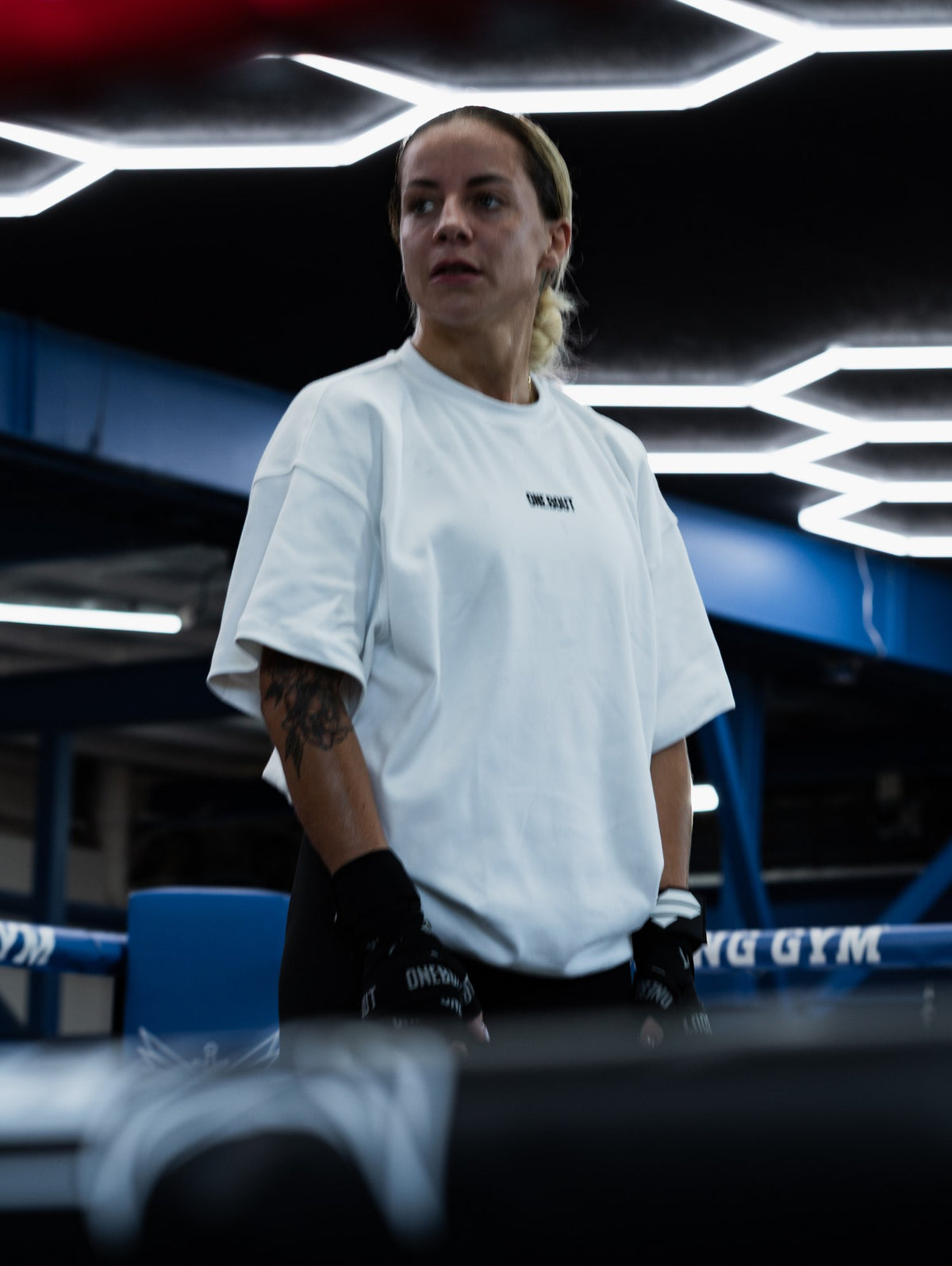 Boxer in a white women's One Bout OWN THE ROUND oversized tee in the ring at Titan Boxing Gym